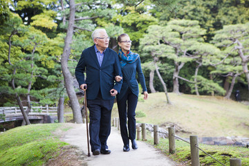 日本庭園を散策するシニアのカップル。