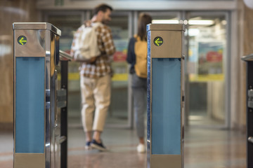 closeup shot of turnstiles and couple of travelers with backpacks behind