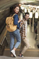 stylish couple of tourists with backpacks at subway station