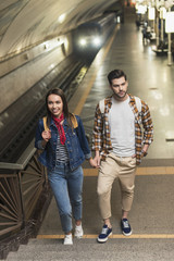 couple of stylish tourists with backpacks at subway station
