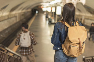 rear view of travelers with backpacks going downstairs at subway station