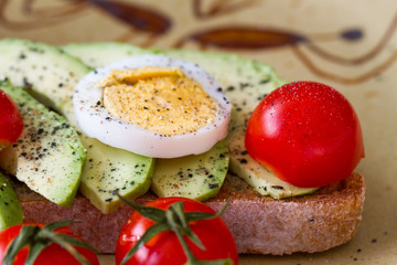 Slice of toast bread with avocado, eggs and cherry tomatoes