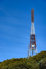 Mountain top communications tower in Costa Rica, painted aviation red and white and covered with antennas
