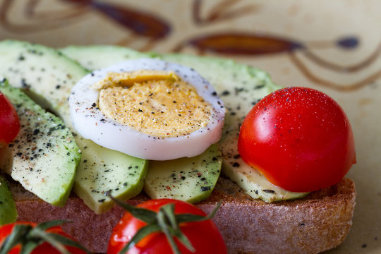 Slice of toast bread with avocado, eggs and cherry tomatoes