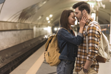Fototapeta premium side view of female traveler embracing boyfriend at subway station