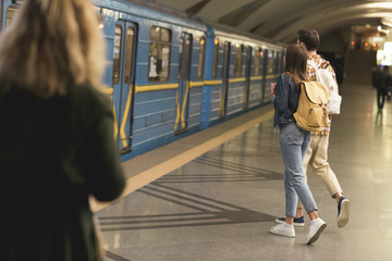 rear view of stylish tourists with backpacks at metro station