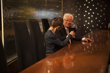 Obraz na płótnie Canvas ロマンスグレーの男性が、エレガントな女性とワイングラスを手に乾杯している。