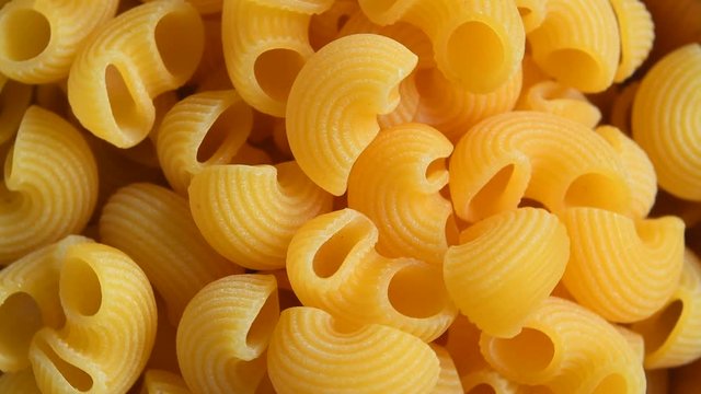 Uncooked macaroni pasta rotating background