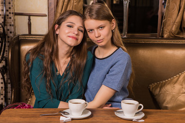 Two happy women drinking coffee in cafe