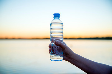 Girl holding a bottle of drinking water at sunset