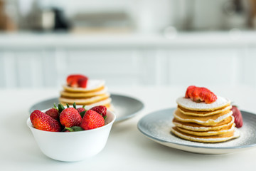 pancakes with ripe strawberries on table at kitchen