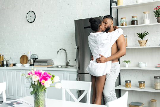 Sensual African American Couple Standing And Kissing At Kitchen