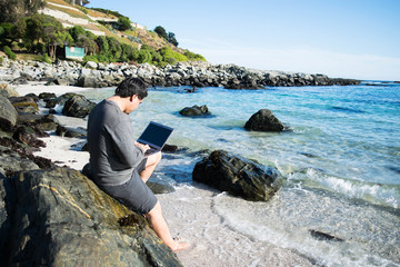 Man with a laptop on beach in the water