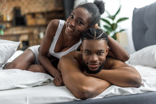 happy african american couple in underwear looking at camera in bedroom