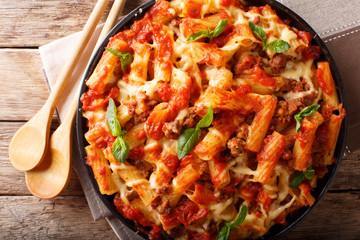 Casserole ziti pasta with minced meat, tomatoes, herbs and cheese close-up. Horizontal top view