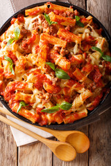 Casserole ziti pasta with minced meat, tomatoes, herbs and cheese close-up. Vertical top view