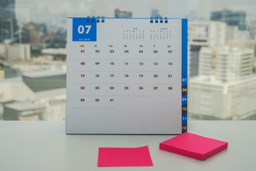 close up July calendar with pink mock up postit for leaving message to remind meeting and appointment
