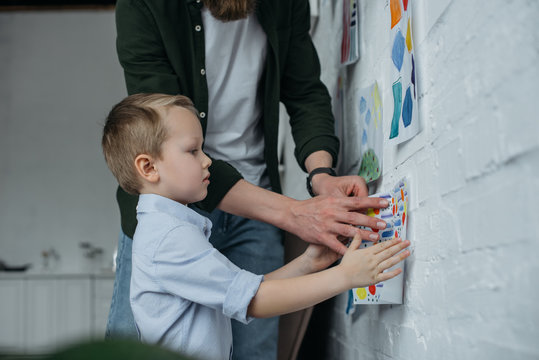 partial view of family hanging childish drawing on wall together at home
