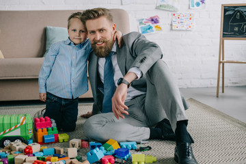 little boy hugging smiling father in business suit at home, work and life balance concept