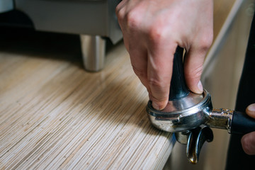 coffee brewing process. professional barista pressing coffee powder in the holder with a tamper