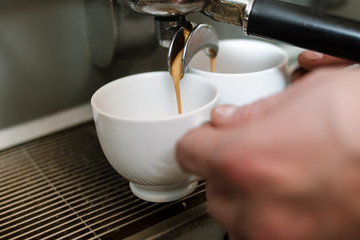 caffeine dependency concept. morning energy drink. barista making two cups of hot fresh strong coffee. beverage pouring from machine