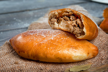 Broken pie with meat on flax close-up. Advertising still life from baking.
