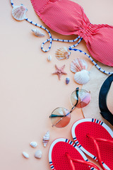 Summer fashion flatlay with gradient round sunglasses, straw hat, flats and red striped bikini top. Decorated with sea shells. Perfect beach set for holidays on the sea. Marina style.