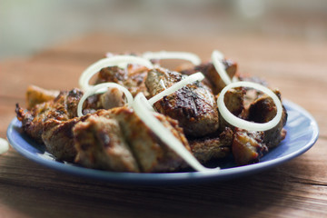 kebab, juicy fried pieces of meat with onion on wooden background