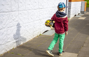 Young walking along white wall with longboard