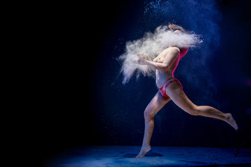 Old fat naced female dancer tries to dance in the studio during photoshoot with flour on a black...