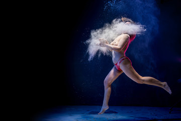 Old fat naced female dancer tries to dance in the studio during photoshoot with flour on a black background © keleny