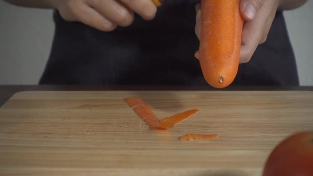 Slow motion - Close up of woman making healthy food and chopping carrot on cutting board in the kitchen.