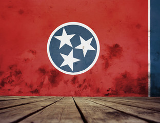 The floor of planks and plastered wall with a painted Tennessee flag. 