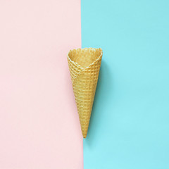 Creative still life of empty waffle cone on pink and blue background. Top view.