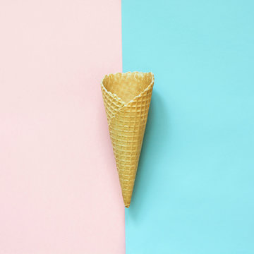 Creative still life of empty waffle cone on pink and blue background. Top view.