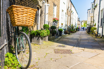 Bike parked against a wall in a small traditional British street mews with classic English Victorian houses in a sunny day