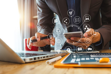Obraz premium businessman hand working with laptop computer, tablet and smart phone in modern office with virtual icon diagram at modernoffice in morning light 