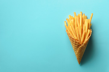 Fried potatoes in waffle cones on blue background. Hot salty french fries with tomato sauce, basil leaves. Fast food, junk food, diet concept. Top view. Minimal style. Pop art design, creative concept - obrazy, fototapety, plakaty
