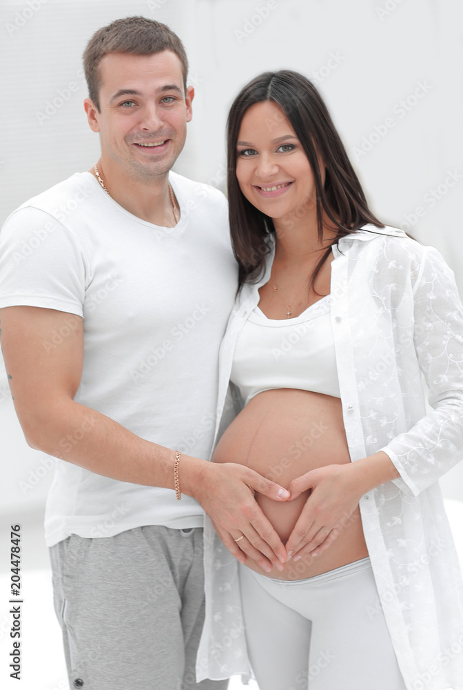 Wall mural husband and pregnant wife with folded hands in the shape of a heart on his tummy