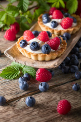  Dessert tarts with raspberries and blueberries on a wooden table.