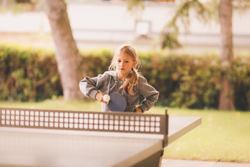 Young blond girl playing table tennis outdoor - obrazy, fototapety, plakaty