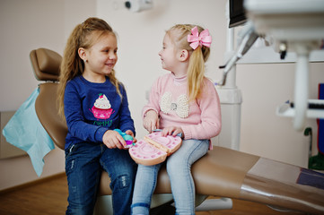 Two cutie little baby girls at dentist chair. Children dental.