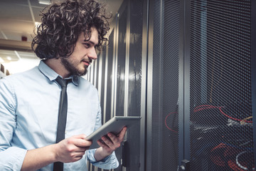 male technician inspecting and working on servers in server room