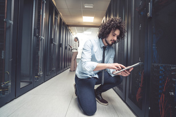 male technician inspecting and working on servers in server room