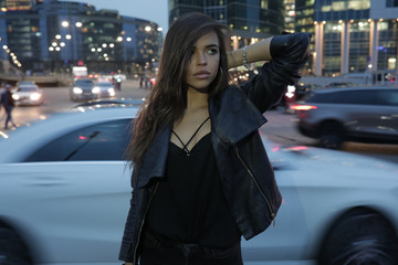 Fototapeta premium Beautiful woman on a background of a night city and passing cars.