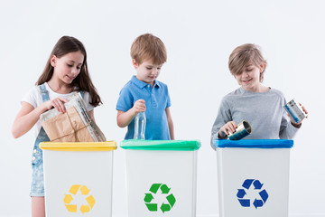 Children segregating paper into bin - obrazy, fototapety, plakaty