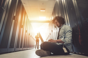 male technician inspecting and working on servers in server room
