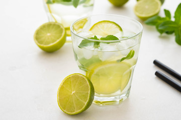 Mojito cocktail on a white marble background. Mint, lime, ice ingredients and bar shaker.