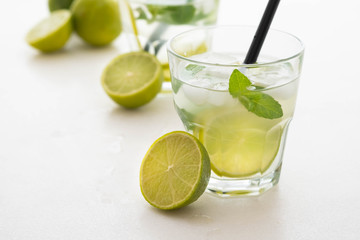 Mojito cocktail on a white marble background. Mint, lime, ice ingredients and bar shaker.