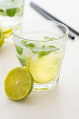 Mojito cocktail on a white marble background. Mint, lime, ice ingredients and bar shaker.
